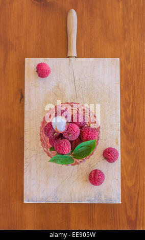 Vista dall'alto di un bel colore rosa ciotola di vetro pieno con i litchi frutti e semi lychee pelati sulla parte superiore. Foto Stock