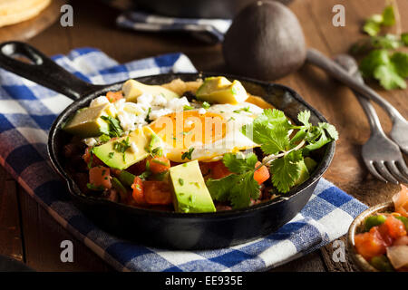 In casa Heuvos Rancheros con Avocado e coriandolo Foto Stock