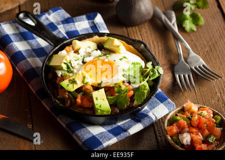 In casa Heuvos Rancheros con Avocado e coriandolo Foto Stock