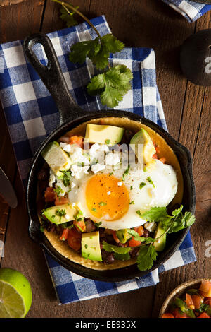 In casa Heuvos Rancheros con Avocado e coriandolo Foto Stock