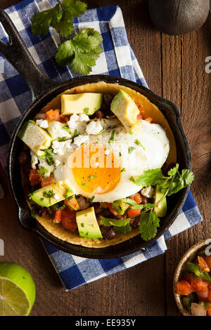 In casa Heuvos Rancheros con Avocado e coriandolo Foto Stock