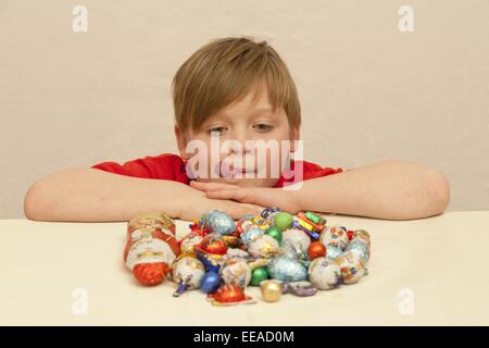 Ragazzo con un mucchio di dolci di Natale davanti a lui Foto Stock