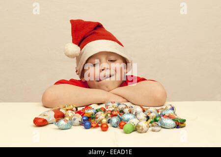 Ragazzo con un mucchio di dolci di Natale davanti a lui Foto Stock