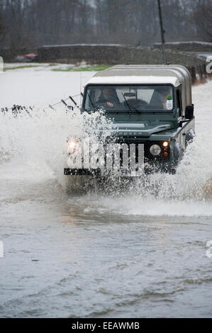 Land Rover guidando attraverso invaso una strada in Cumbria Foto Stock