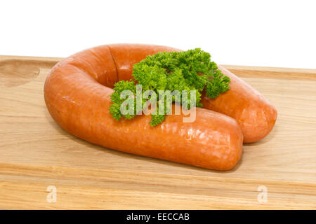 Olandese salsiccia affumicata su un tagliere di legno guarnita con un ciuffo di prezzemolo riccio Foto Stock