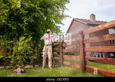 Un uomo è la pulizia staccionata in legno con potenza elettrica la rondella Foto Stock