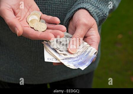 Primo piano di un uomo che detiene banconote in moneta inglese banconote e monete in contanti finanzia il business concept Inghilterra Regno Unito Regno Unito Gran Bretagna Foto Stock