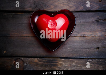 Candela rossa a forma di cuore su sfondo di legno Foto Stock