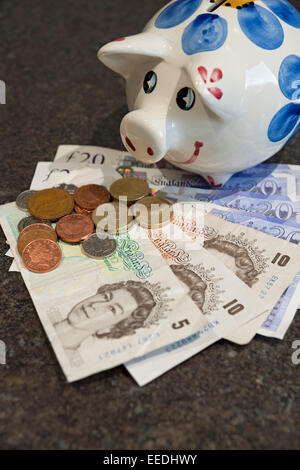 Primo piano di Piggy Bank e banconote in moneta inglese banconote e monete in contanti finiscono il business concept Inghilterra Regno Unito Regno Unito Gran Bretagna Foto Stock
