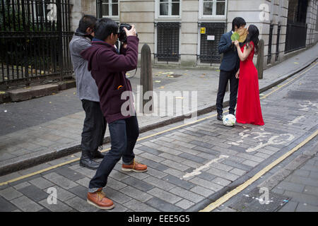 Asian fotografo fotografare una coppia cinese per le loro foto del matrimonio. Londra, Regno Unito. Questa è una visione comune come coppie provenienti da Asia hanno le loro fotografie fatto come prima del loro effettivo giorno di nozze indossando il loro abito e tuta. Foto Stock