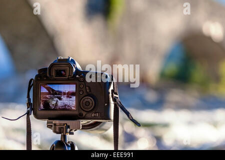 Una fotocamera reflex digitale su un treppiede fotografare un ponte di paesaggio. Il Ponte di Bobbio, Emilia Romagna. Italia Foto Stock