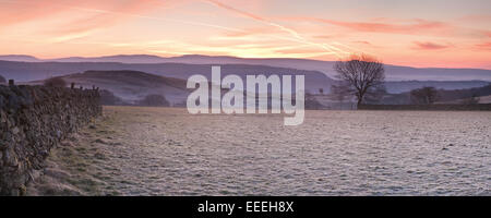 Frost campi coperti e stalattite parete guardando verso il lontano fells e montagne di sunrise Foto Stock