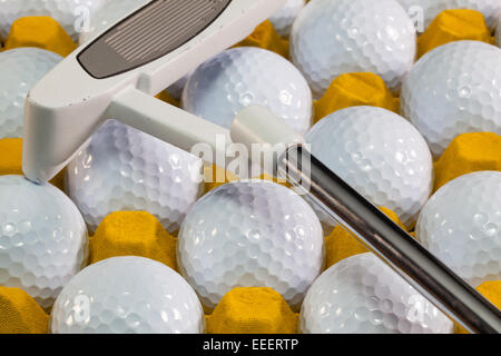 White palline da golf nella casella gialla e attrezzature da golf Foto Stock