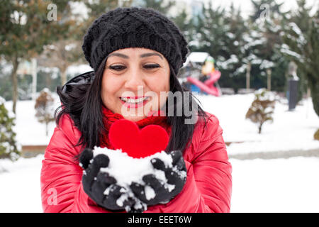 Capelli neri donne turche tenendo un cuore rosso in mano e celebra il giorno di San Valentino con sfondo innevato Foto Stock