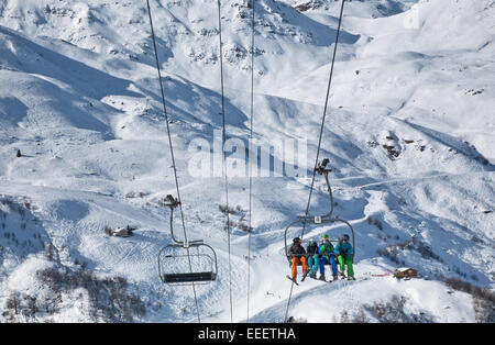 Quattro persone ride lo skilift fino alla montagna nelle Alpi, Francia Foto Stock