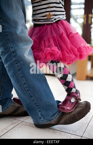 Bambina in piedi sul suo padre piedi danzanti. Foto Stock