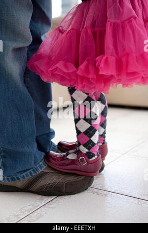 Bambina in piedi e il bilanciamento sul suo padre i piedi. Foto Stock