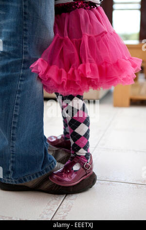 Bambina in piedi e il bilanciamento sul suo padre i piedi. Foto Stock