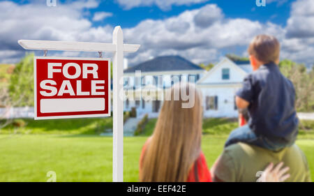 Curioso famiglia rivolta per la vendita immobiliare di segno e bella casa di nuova costruzione. Foto Stock