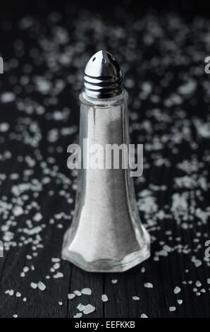 Close up di sale shaker su tavoli in legno nero con sale tutti su di esso Foto Stock