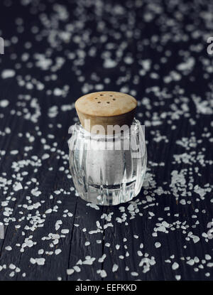 Sale rustico shaker su tavoli in legno nero con sale tutti su di esso Foto Stock