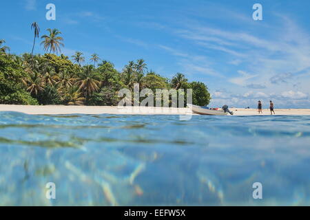 Incontaminata isola dei Caraibi con vegetazione tropicale e una barca sulla spiaggia con i turisti, visto dalla superficie del mare, Panama Foto Stock