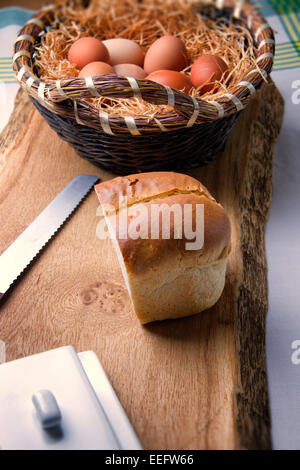 Filone di pane e cesto di fresco posate le uova di gallina Foto Stock