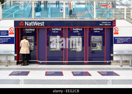 NAT West Bank Back View Woman che estrae contanti dai bancomat dell'atrio passeggeri principale presso la stazione ferroviaria di Liverpool Street Inghilterra Regno Unito Foto Stock