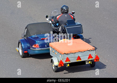 Il pilota del motociclo con sidecar di traino di un piccolo rimorchio sul Regno Unito autostrada oscurata digitalmente numero di targa M25 Autostrada Essex England Regno Unito Foto Stock