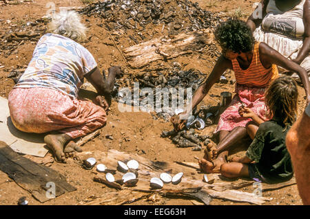 Tiwi le donne Aborigene la cottura di conchiglia, Isole Tiwi, Territorio del Nord, l'Australia Foto Stock