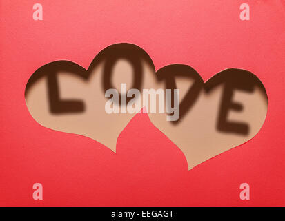 Due cuori nella sfinestratura della carta rossa con la parola 'amore' all'interno.Card design. Foto Stock