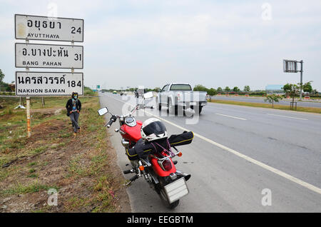 Donna tailandese di equitazione motocicletta del trinciapaglia sul modo in cui andare a Ayutthaya con guidepost o segni di distanza Foto Stock