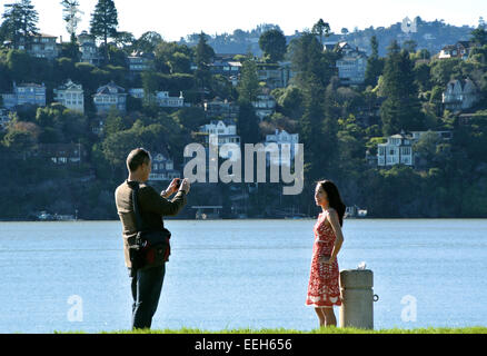 L uomo si prende la foto della donna in Tiburon California con Belvedere Isola in background Foto Stock