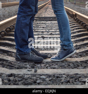 Coppia giovane kissing a rotaie ferroviarie. Due persone in piedi in amore al giorno di estate Foto Stock