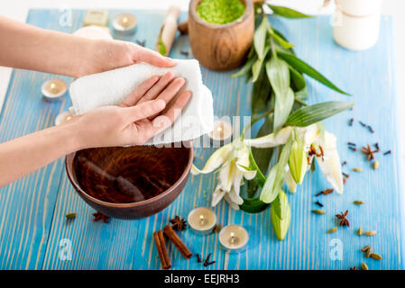 Asciugare le mani con asciugamano da bagno sul tavolo di legno con spa roba in background Foto Stock