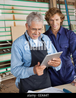 Carpenter con tavoletta digitale con un collega Foto Stock