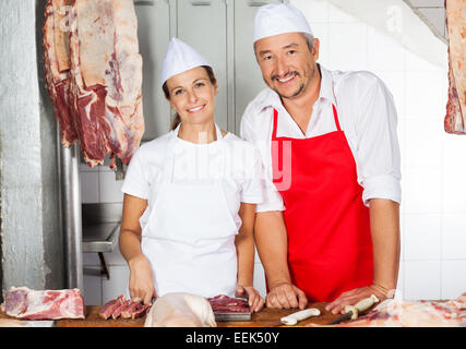 Fiducioso macellai permanente al contatore in macelleria Foto Stock