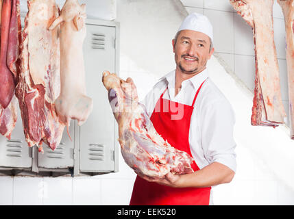 Butcher tenendo la carne in macelleria Foto Stock