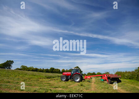 Agricoltore la falciatura di erba per haylage in estate in Norfolk, Regno Unito Foto Stock