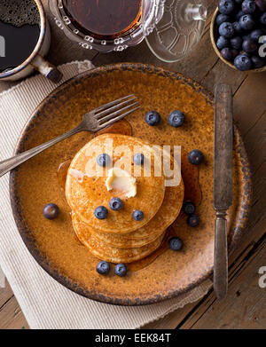 Pancake con mirtilli e sciroppo d'acero su un rustico tavolo. Foto Stock