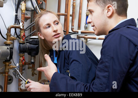 Trainee femmina Plumber lavorando sul centro di caldaia di riscaldamento Foto Stock