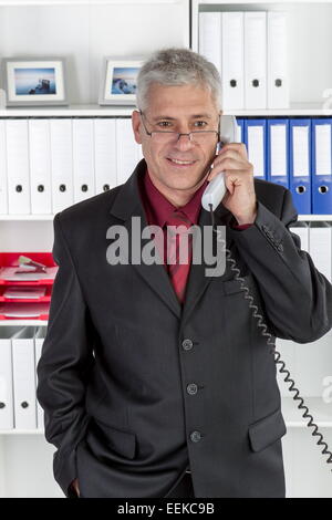 Mann mittleren altera im Büro telefoniert, uomo di mezza età nel suo ufficio, telefonare Foto Stock