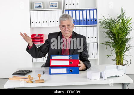 Mann mittleren altera sitzt im Büro und gestikuliert, uomo di mezza età, seduto nel suo ufficio, gesticulating Foto Stock