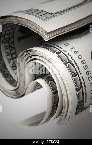 Twisted dollari degli Stati Uniti. Frammento di centinaia di banconote in USD su sfondo grigio. Messa a fuoco selettiva Foto Stock