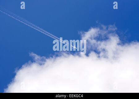 Volo aereo sul cielo blu con nuvole bianche e contrails. Foto Stock
