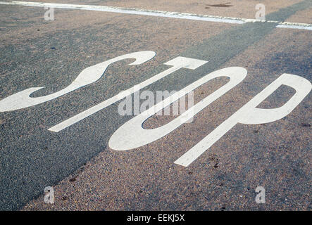 La parola STOP dipinta su una strada asfaltata. Foto Stock