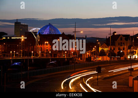Belfast City Centre skyline al tramonto con luce percorsi di traffico sulla Queen Elizabeth Bridge Foto Stock