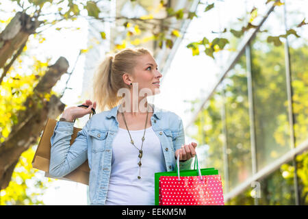 Ragazza camminare per la strada con le borse della spesa Foto Stock