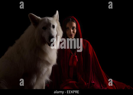 Donna che indossa un cappuccio rosso in posa di studio con il suo cane Foto Stock