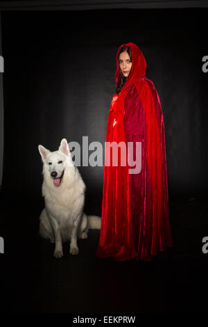 Donna che indossa un cappuccio rosso in posa di studio con il suo cane Foto Stock